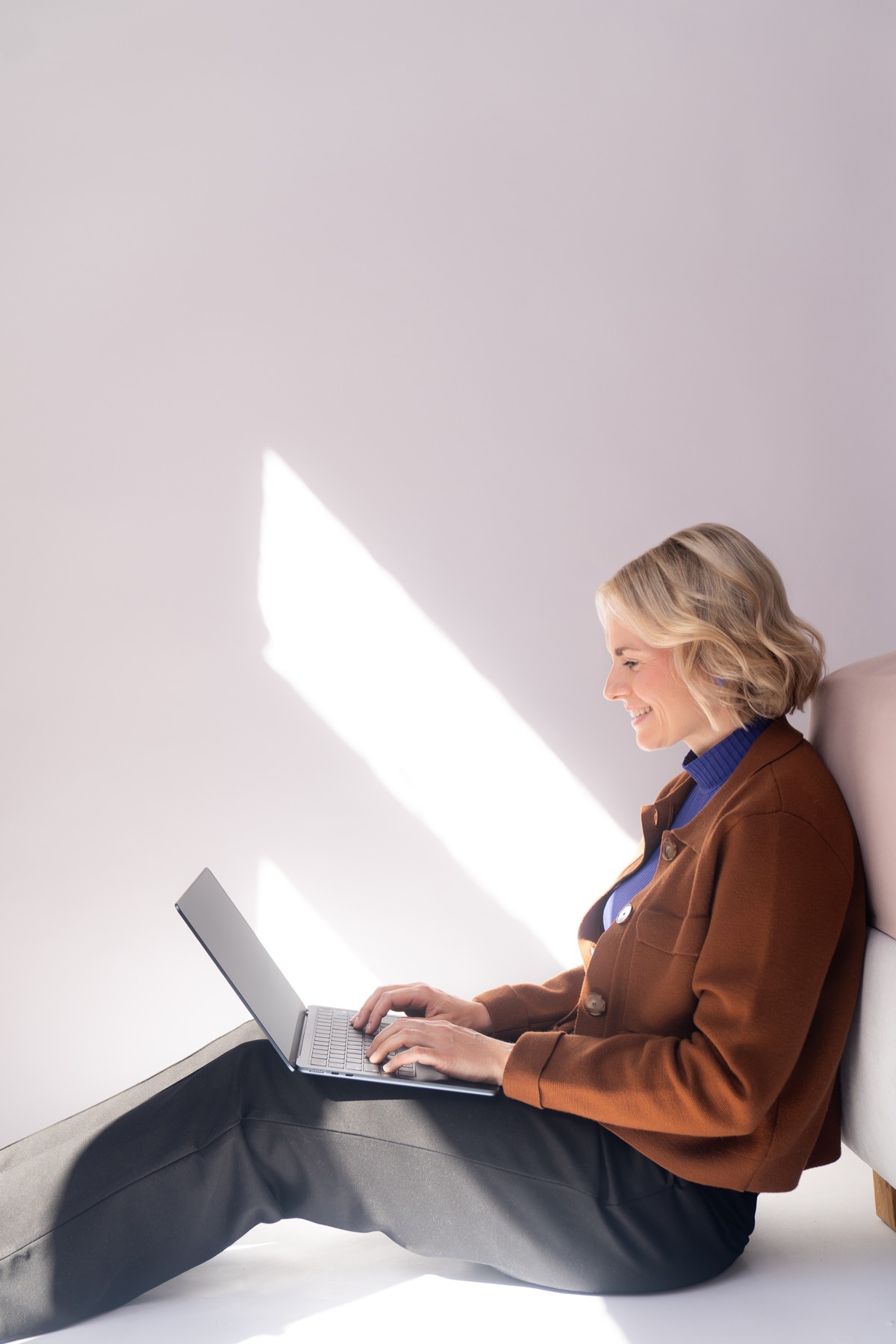 Judith Storm sitzt mit Laptop im Sonnenlicht auf dem Boden.